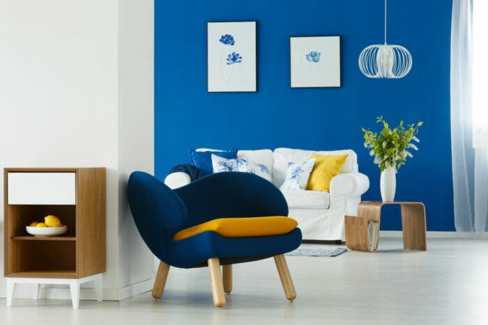 A living room with blue walls and a yellow chair designed by a product design agency in Swindon.